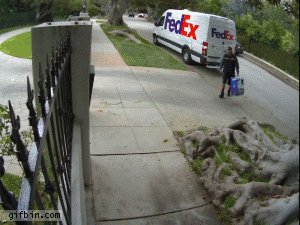 livreur Fedex balance une télévision par-dessus une clôture