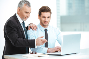 Stock image, manager en costume pointe du doigt l’écran d’un employé