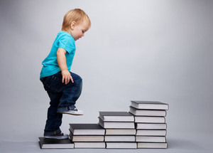 un bébé monte des escaliers construit avec des livres